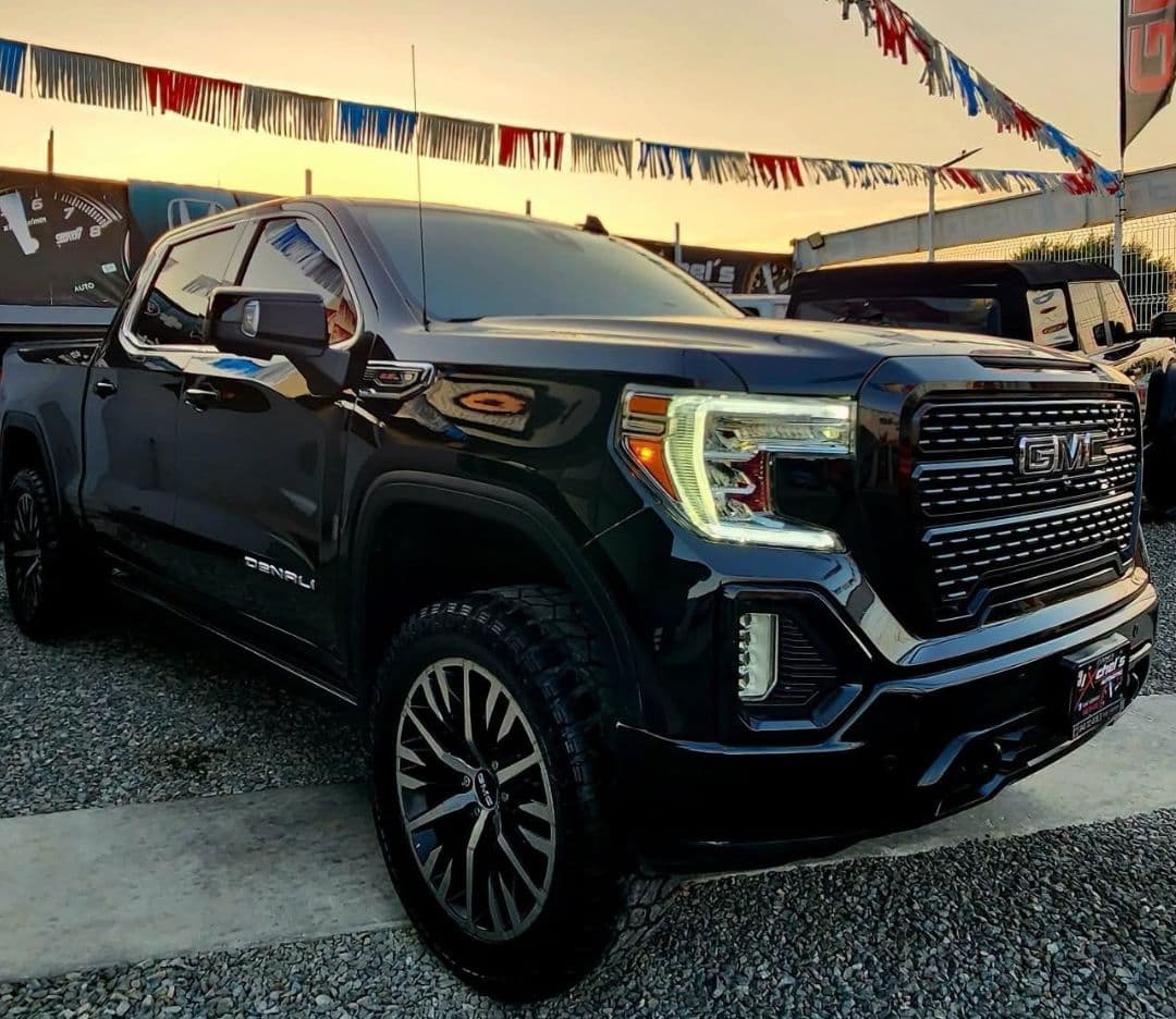 GMC Sierra Denali negra en el lote de Ixchel's Automotriz al atardecer