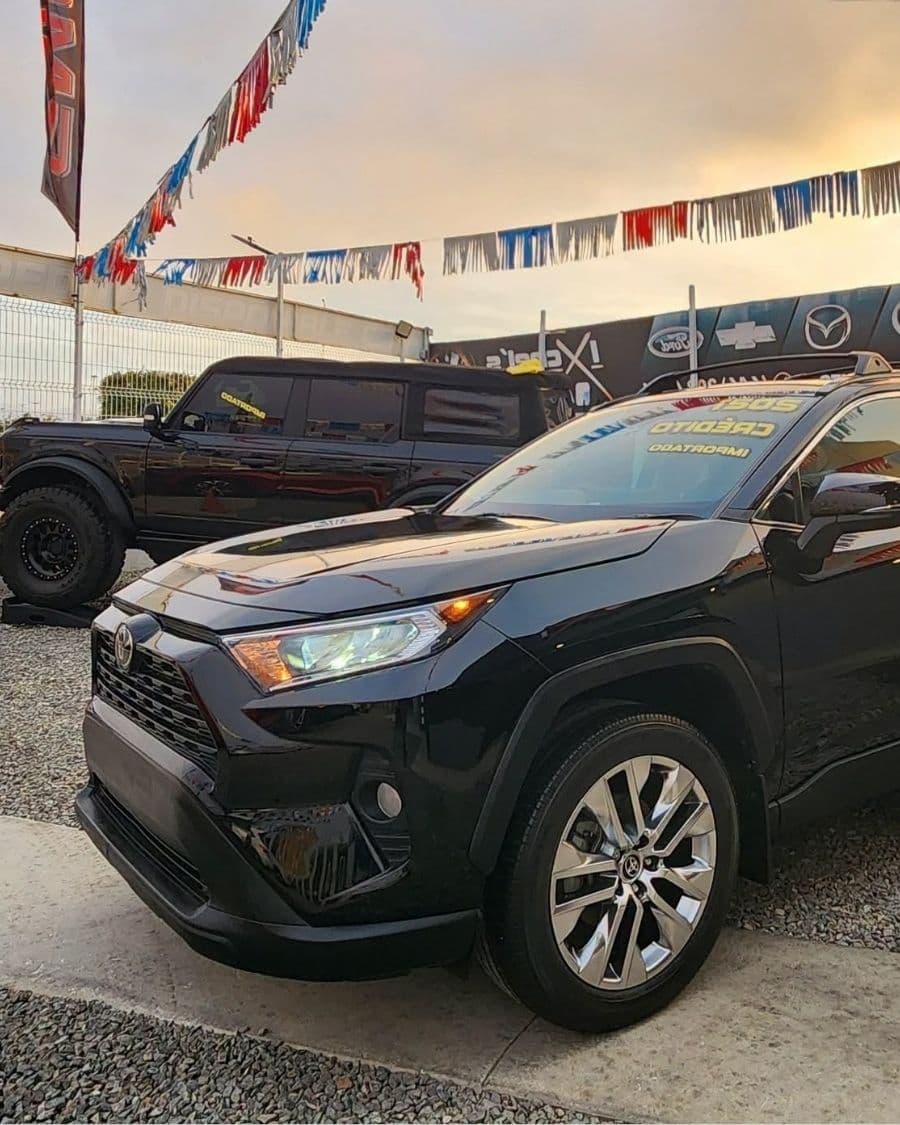 Toyota RAV4 negra en el lote de Ixchel's Automotriz al atardecer, con letrero de crédito en el parabrisas